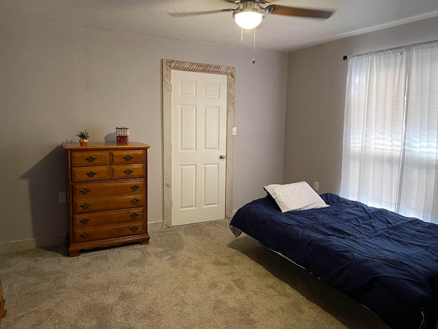 bedroom with a textured ceiling, light carpet, and ceiling fan