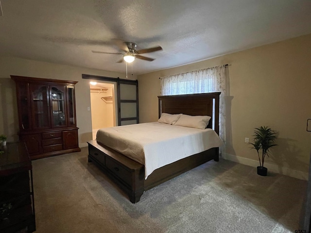 bedroom featuring a barn door, carpet flooring, ceiling fan, and a textured ceiling