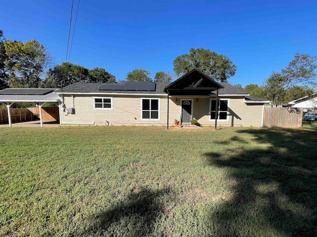 rear view of property featuring solar panels and a lawn