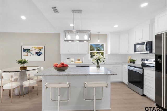 kitchen featuring pendant lighting, stainless steel appliances, a kitchen breakfast bar, white cabinets, and a kitchen island