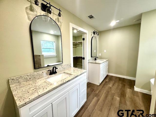 641 N Weldon St, Frankston, TX 75763 - bathroom featuring wood finished floors, two vanities, a walk in closet, and baseboards