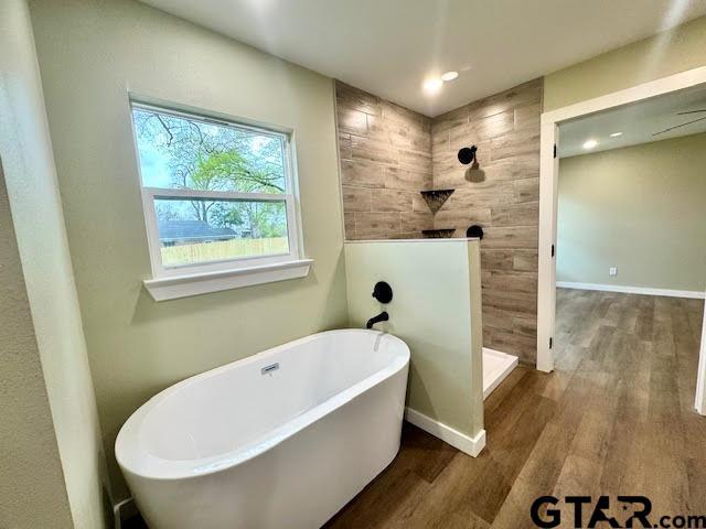 641 N Weldon St, Frankston, TX 75763 - bathroom with wood finished floors, a soaking tub, walk in shower, and baseboards
