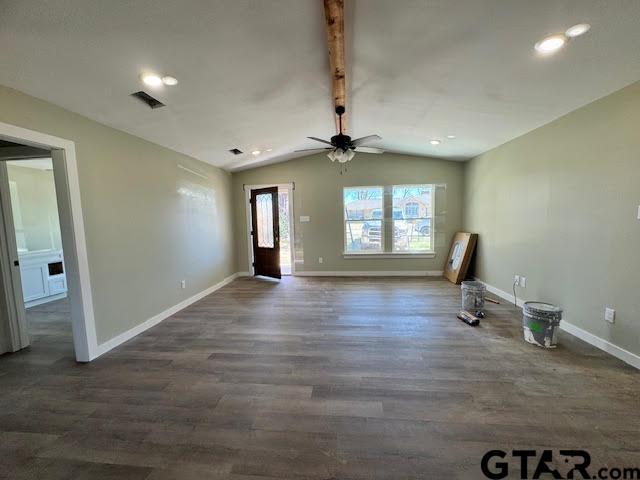 unfurnished living room featuring visible vents, baseboards, wood finished floors, and vaulted ceiling with beams