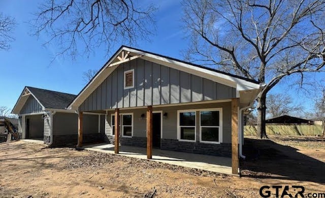 view of front facade with covered porch, board and batten siding, and stone siding