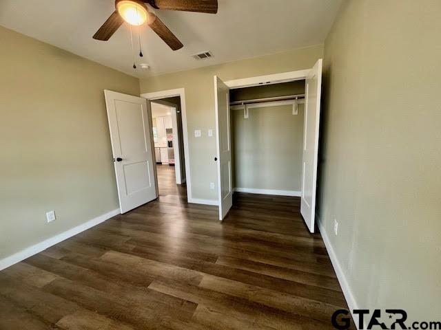 641 N Weldon St, Frankston, TX 75763 - unfurnished bedroom featuring dark wood-style flooring, baseboards, a closet, and a ceiling fan