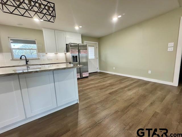 641 N Weldon St, Frankston, TX 75763 - kitchen with stainless steel refrigerator with ice dispenser, dark stone countertops, white cabinetry, decorative backsplash, and dark wood finished floors