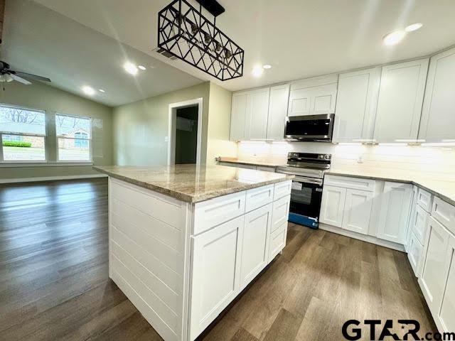 641 N Weldon St, Frankston, TX 75763 - kitchen featuring stainless steel appliances, dark wood finished floors, a kitchen island, decorative backsplash, and light stone counters