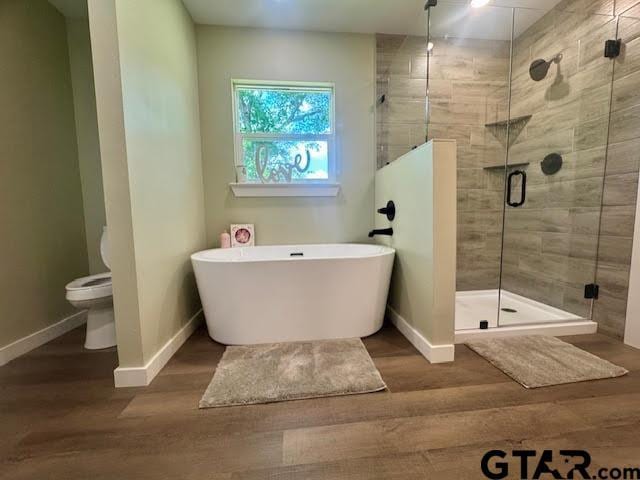641 N Weldon St, Frankston, TX 75763 - full bathroom featuring a freestanding tub, baseboards, a shower stall, and wood finished floors
