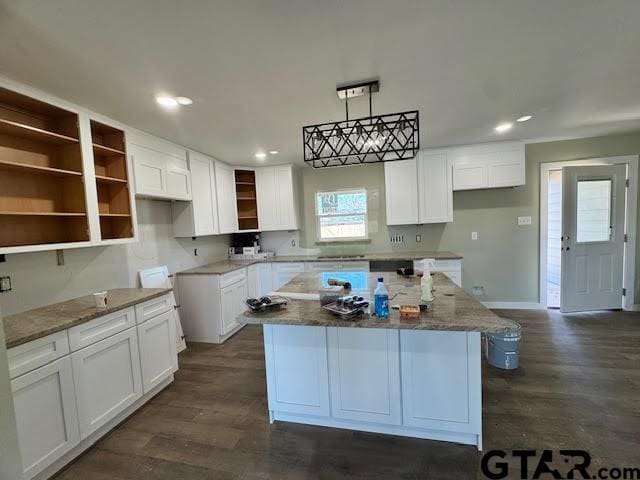 kitchen featuring a center island, pendant lighting, white cabinets, and light stone counters