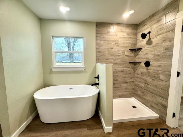 641 N Weldon St, Frankston, TX 75763 - full bath featuring a soaking tub, wood finished floors, a tile shower, and baseboards