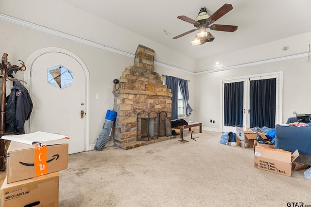 carpeted living area with vaulted ceiling, a stone fireplace, and ceiling fan