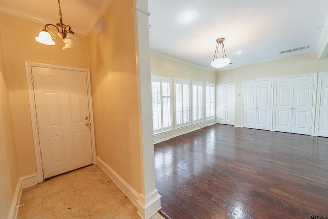 entryway with ornamental molding, hardwood / wood-style floors, and an inviting chandelier