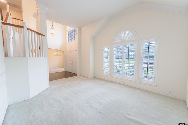 carpeted spare room featuring ornamental molding, a chandelier, and vaulted ceiling