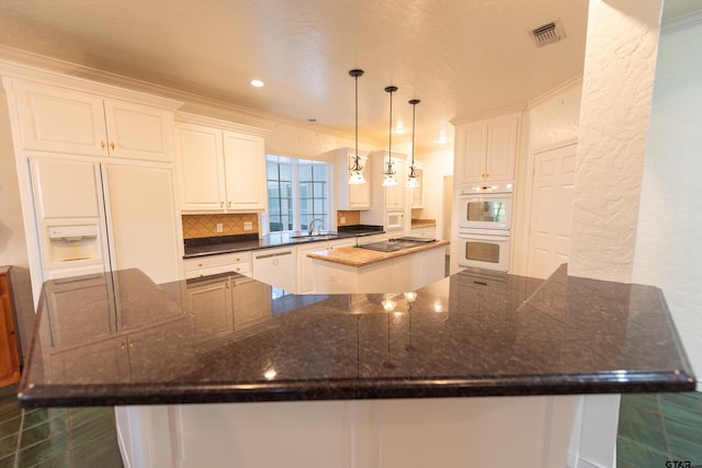 kitchen with white cabinetry, decorative light fixtures, ornamental molding, and a center island