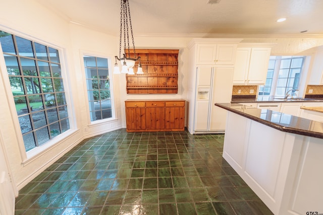 kitchen with white cabinetry, sink, white fridge with ice dispenser, hanging light fixtures, and decorative backsplash