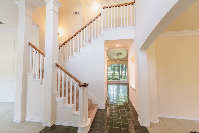 stairs featuring decorative columns, a towering ceiling, and ornamental molding