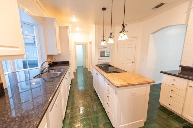 kitchen featuring white cabinets, sink, white appliances, decorative light fixtures, and dark stone countertops