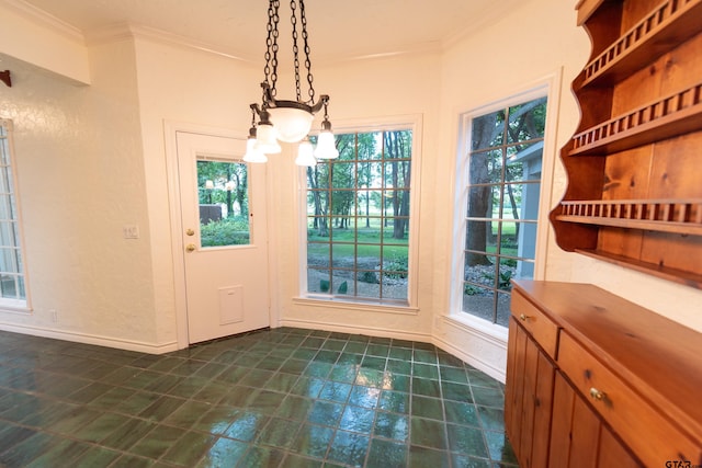 unfurnished dining area with ornamental molding, dark tile patterned flooring, and a chandelier