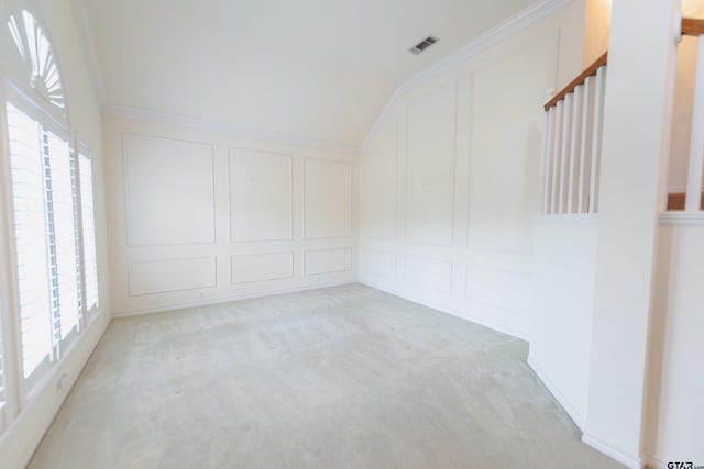 carpeted empty room featuring ornamental molding, lofted ceiling, and a healthy amount of sunlight