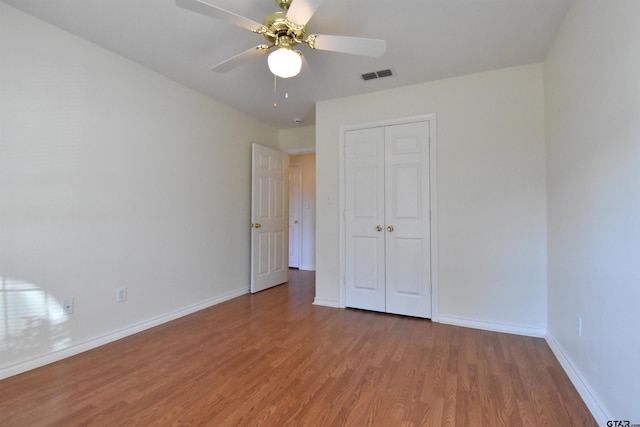 unfurnished bedroom featuring ceiling fan, wood-type flooring, and a closet