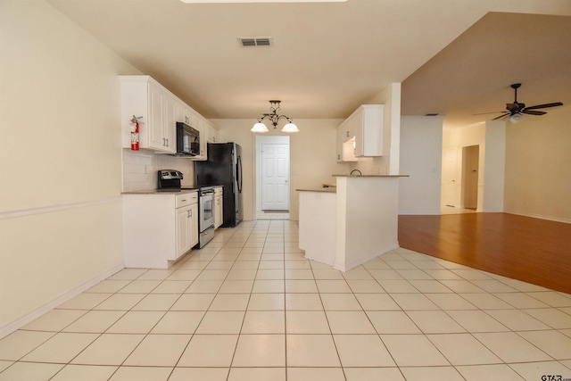 kitchen featuring white cabinetry, light tile patterned floors, fridge, stainless steel range with electric cooktop, and ceiling fan with notable chandelier