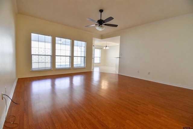 empty room with light hardwood / wood-style floors, ceiling fan with notable chandelier, and ornamental molding