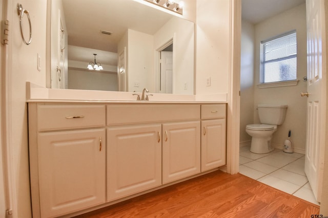 bathroom featuring tile patterned flooring, vanity, a chandelier, and toilet