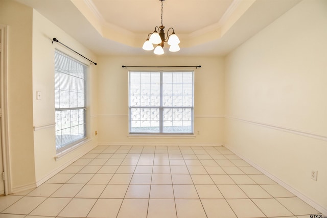 spare room with a chandelier, a raised ceiling, plenty of natural light, and light tile patterned flooring