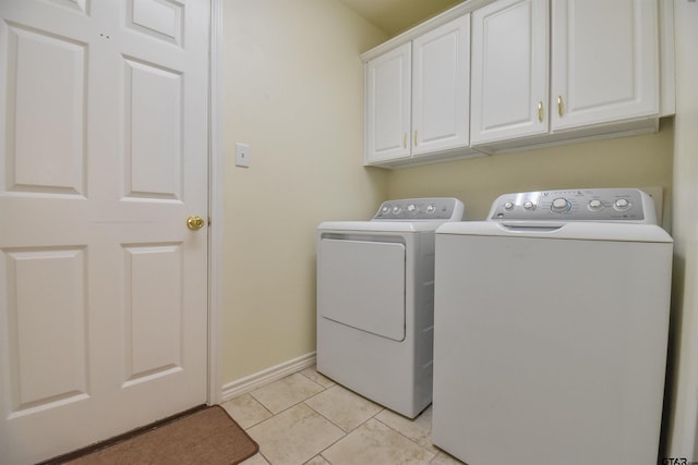 laundry area featuring washing machine and clothes dryer, light tile patterned floors, and cabinets