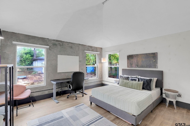 bedroom featuring multiple windows, vaulted ceiling, and light wood-type flooring