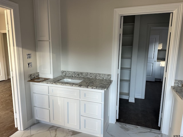 kitchen with sink, white cabinets, and light stone counters