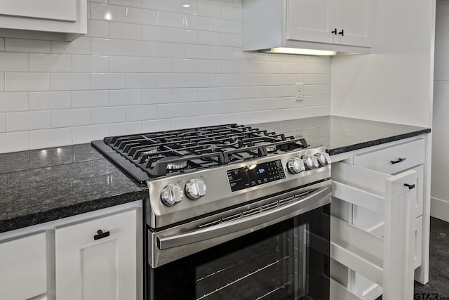 kitchen with white cabinets, dark stone counters, stainless steel range with gas stovetop, and decorative backsplash