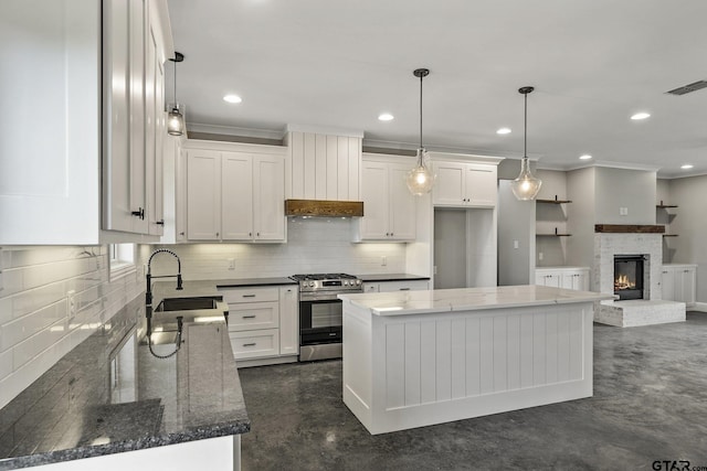 kitchen featuring stainless steel gas range, a sink, and white cabinetry