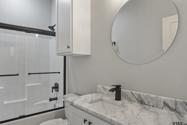 full bathroom featuring toilet, shower / bath combination with glass door, and vanity