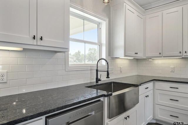 kitchen featuring white cabinets, dishwasher, backsplash, dark stone countertops, and a sink