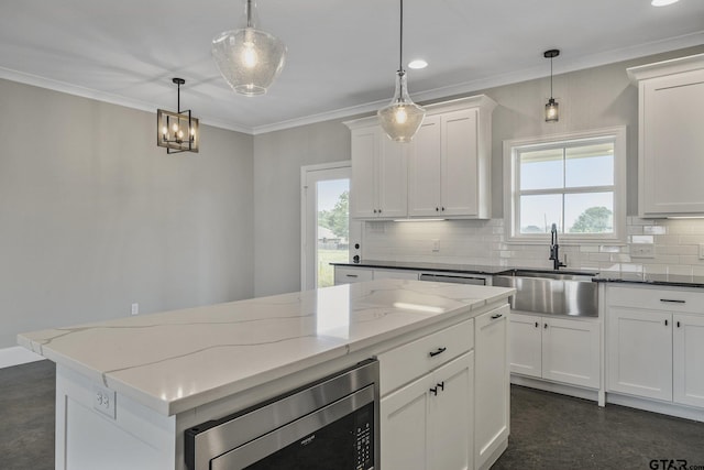 kitchen featuring a sink, white cabinetry, ornamental molding, tasteful backsplash, and stainless steel microwave