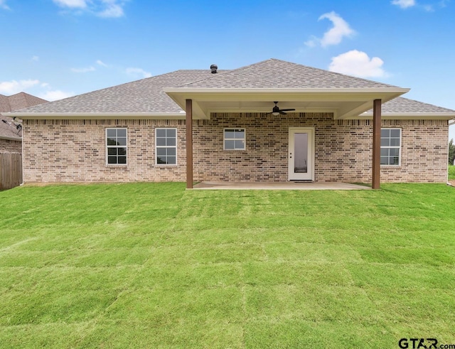 rear view of property featuring a lawn, ceiling fan, roof with shingles, a patio area, and brick siding