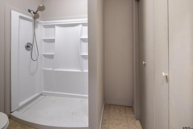 bathroom featuring tile patterned floors, toilet, and a shower