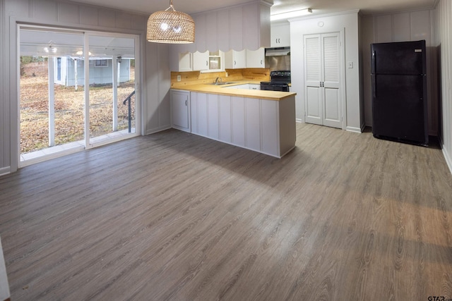 kitchen featuring light wood-type flooring, kitchen peninsula, hanging light fixtures, black appliances, and white cabinets