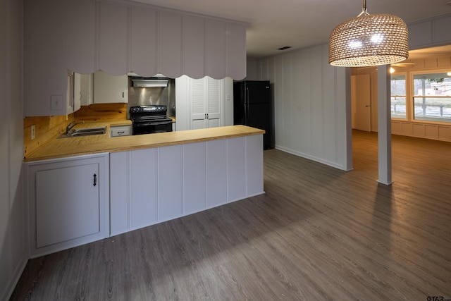 kitchen featuring kitchen peninsula, black appliances, dark hardwood / wood-style flooring, and decorative light fixtures