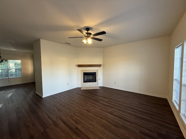 203 Macarthur St, Tyler, TX 75704 - unfurnished living room with baseboards, dark wood-type flooring, a fireplace with flush hearth, ceiling fan, and a chandelier
