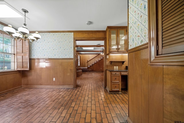 1101 Canada St, Jacksonville, TX 75766 - kitchen featuring a chandelier, brick flooring, a wainscoted wall, wallpapered walls, and brown cabinetry