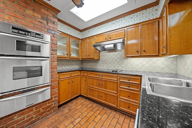 1101 Canada St, Jacksonville, TX 75766 - kitchen with under cabinet range hood, stainless steel double oven, a warming drawer, black electric stovetop, and brown cabinets