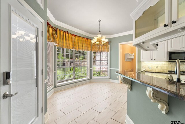 801 Wilder Way, Tyler, TX 75703 - kitchen featuring stainless steel microwave, tasteful backsplash, white cabinetry, crown molding, and glass insert cabinets