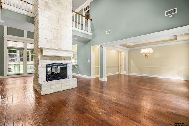 801 Wilder Way, Tyler, TX 75703 - unfurnished living room featuring a towering ceiling, a stone fireplace, ornamental molding, a chandelier, and hardwood / wood-style flooring