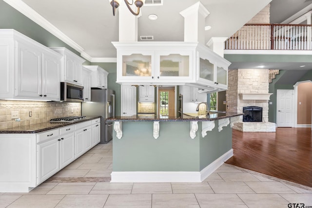 801 Wilder Way, Tyler, TX 75703 - kitchen featuring appliances with stainless steel finishes, glass insert cabinets, a kitchen breakfast bar, white cabinets, and a towering ceiling
