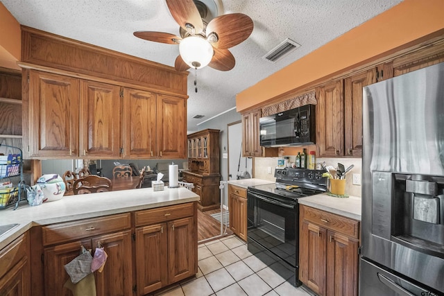10236 County Road 2253, Tyler, TX 75707 - kitchen featuring black appliances, a textured ceiling, light countertops, light tile patterned floors, and brown cabinets