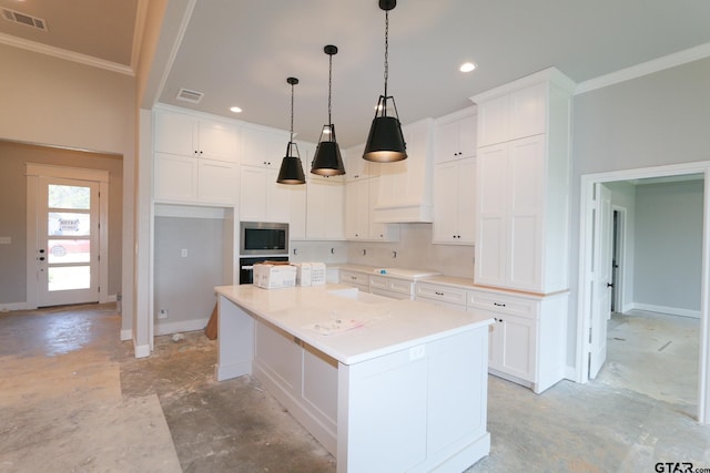 kitchen featuring white cabinets, hanging light fixtures, a kitchen island, and ornamental molding