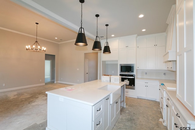 kitchen featuring white cabinets, stainless steel appliances, pendant lighting, and an island with sink