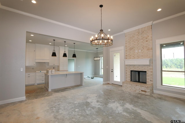 kitchen featuring crown molding, a kitchen island, decorative light fixtures, a brick fireplace, and white cabinets